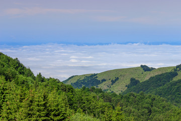 Fototapeta na wymiar Beautiful scene of green mountain hills and fog and blue sky