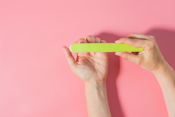 Woman filing nails in colored background
