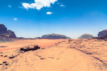 Fototapeta na wymiar Red sand desert at sunny summer day in Wadi Rum, Jordan. Middle East. UNESCO World Heritage Site and is known as The Valley of the Moon.