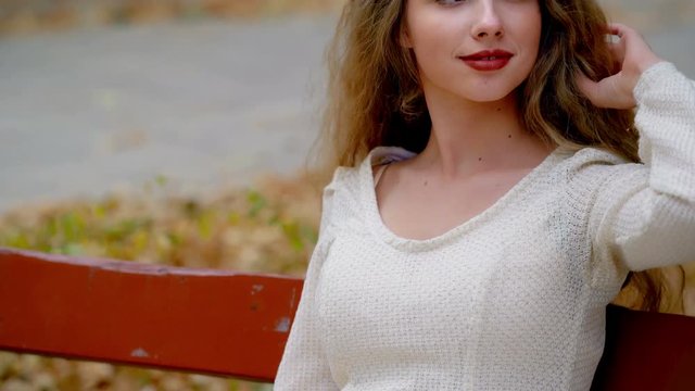 Girl on park bench enjoys freedom, solitude. She has contented face, due to perfect finished school or admission to university. Camera is slowly moving upwards.