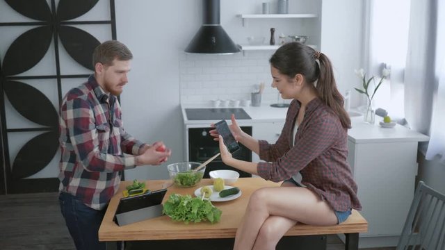 healthy lifestyle, funny laughing Man and woman taking selfie photo on smartphone and fooling around while cooking vegetable salad for lunch in kitchen