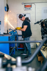 Young motorcycle mechanic using a grinder in the workshop