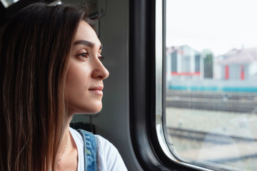 A young girl on the train looking out the window. Good mood in the journey