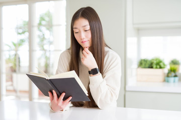 Beautiful Asian woman reading a book serious face thinking about question, very confused idea