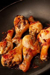 Roasted chicken legs in a black pan
