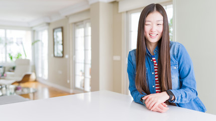 Young beautiful asian woman with long hair wearing denim jacket winking looking at the camera with sexy expression, cheerful and happy face.