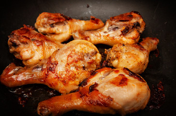 Roasted chicken legs in a black pan