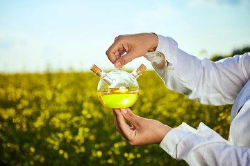 rapeseed oil bottle in hand of an agronomist or biologist on background rape field