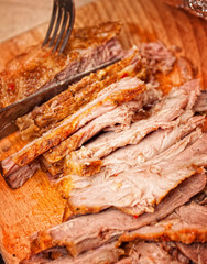 A juicy fresh baked pork with herbs and spice on wooden cutting board.