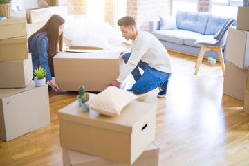 Beautiful young asian couple looking happy, holding a big cardboard box smiling excited moving to a new home