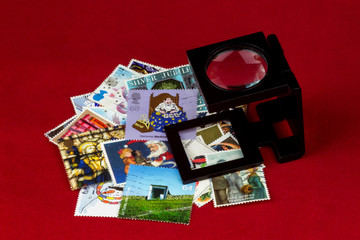Fototapeta na wymiar UK Stamps and Magnifier on a Red Table Cloth