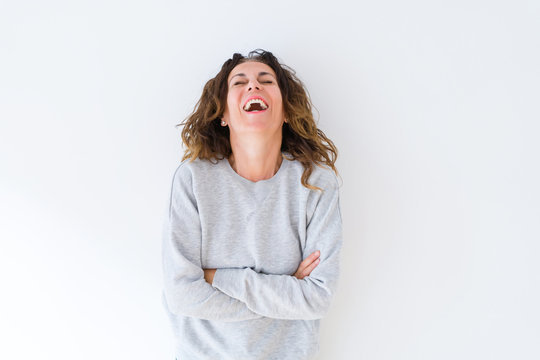 Beautiful middle age woman with curly hair smiling cheerful and happy with arms crossed, laughing with a big smile on face showing teeth over white isolated background