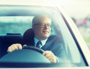 transport, business trip and people concept - happy senior businessman driving car