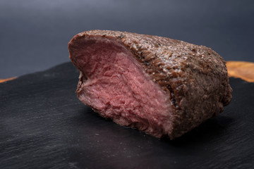 Grass Fed Juicy Corn Roast Beef on black natural stone background.