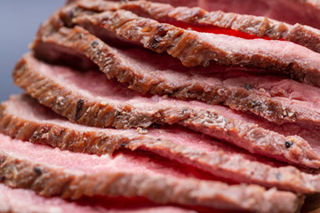 Sliced Grass Fed juicy Corn Roast Beef on natural wood cutting board.