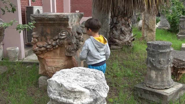 Fethiye Archaeological Museum, Fethiye, Turkey - 8th of April 2019: 4K Child examines and touches centaur face engraved in stone 