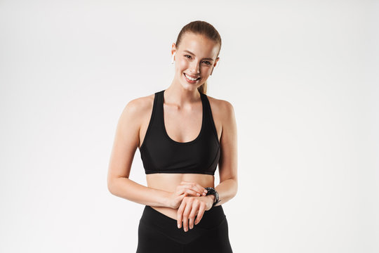 Image of smiling young woman wearing tracksuit using earpods and wrist watch