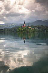 beautiful view on famous bled lake with church on island in stormy sky in julian alps, slovenia
