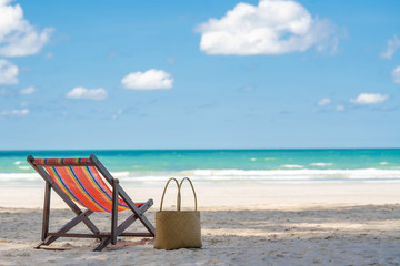 Selective focus of empty colorful beach chair for traveler sunbathe with straw bag on the tropical...