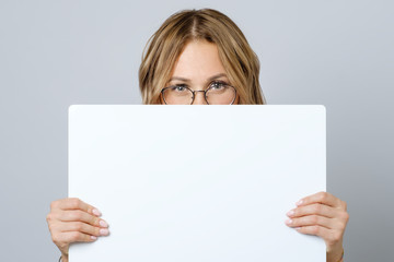 Pretty young woman holding empty blank board isolated