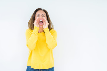 Beautiful middle age woman wearing yellow sweater over isolated background Shouting angry out loud with hands over mouth