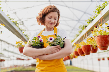 Female gardener embracing potted flowers