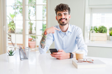 Young business man using smartphone sending a message with surprise face pointing finger to himself