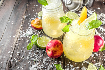 Summer iced peach tea with mint, lime and crushed ice, wooden background copy space
