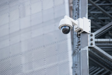 View of a contemporary surveillance video cam attached to a metal girder of the facade of a modern business skyscraper; security video camera on the frontage of an office high-rise 