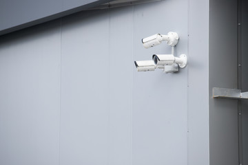 View of a contemporary surveillance video cam attached to a metal girder of the facade of a modern business skyscraper; security video camera on the frontage of an office high-rise 