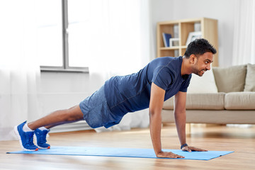 fitness, sport, training and concept - indian man doing push ups at home - obrazy, fototapety, plakaty