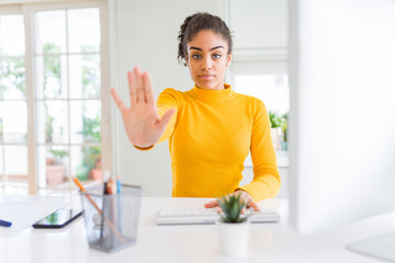Young african american girl working using computer with open hand doing stop sign with serious and confident expression, defense gesture