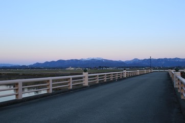 橋から見た夕暮れ時の山々と町の様子です