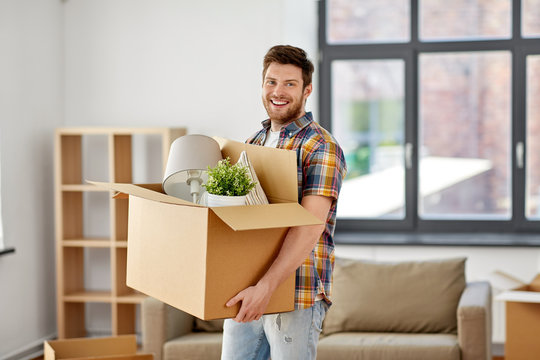 moving, people and real estate concept - happy man with boxes at new home