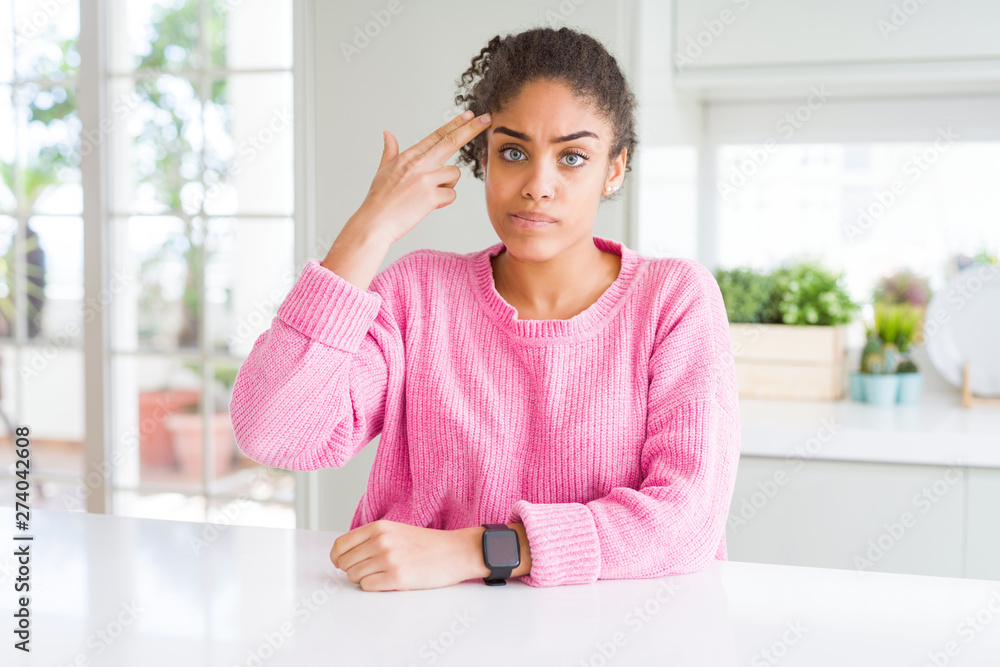 Sticker Beautiful african american woman with afro hair wearing casual pink sweater Shooting and killing oneself pointing hand and fingers to head like gun, suicide gesture.