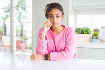 Beautiful african american woman with afro hair wearing casual pink sweater mouth and lips shut as zip with fingers. Secret and silent, taboo talking