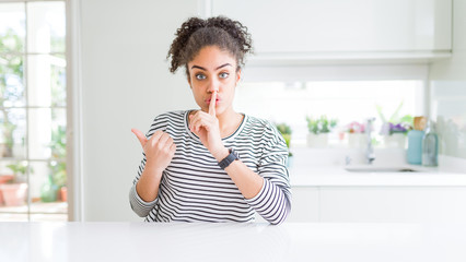 Beautiful african american woman with afro hair wearing casual striped sweater asking to be quiet...