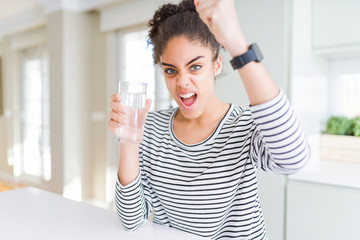 Young african american girl drinking a fresh glass of water annoyed and frustrated shouting with anger, crazy and yelling with raised hand, anger concept
