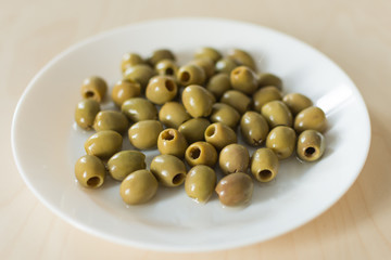 Pickled green olives in a plate on a white background. Olives, healthy eating. Italian cuisine.