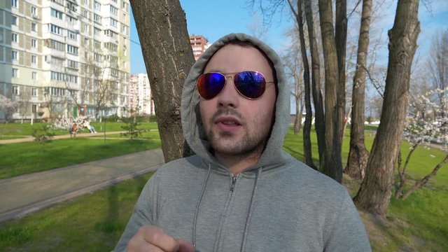 Uncultured man in sunglasses with bad manners picks his nose and spits, disgraceful and shocking behaviour