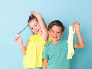 cool, pretty boy and his older sister are playing with homemade slime in front of a blue background...