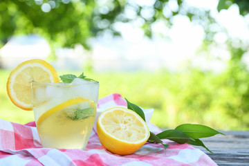 Glasses of lemon juice on a wooden table, summer set, outdoor greed blured background,boke.Water detox