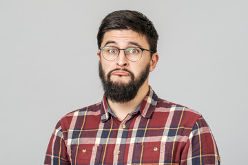 Obraz premium Portrait of unhappy determined european male with serious and worried look against gray background