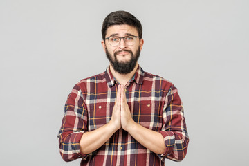 Cute attractive young man with begging expression and gesture