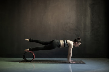 Sporty woman doing Push ups or press ups exercise, phalankasana, variation of Plank pose. Studio shot on black wall