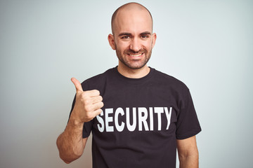 Young safeguard man wearing security uniform over isolated background doing happy thumbs up gesture...