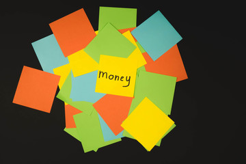 the word money on a piece of yellow paper among multicolored paper