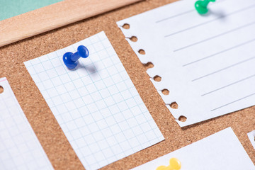 Close up of a paper sheet attached by a button on a corkboard for notes