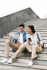 Happy young amazing loving couple business people colleagues outdoors outside on steps reading...