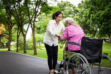 Female caregiver asian or adult nurse support,helping senior woman to stand up from wheelchair in...